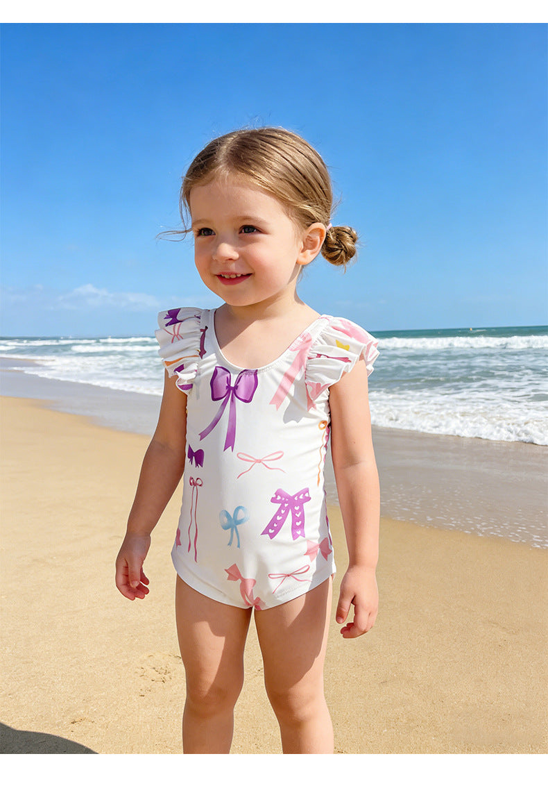 海辺で着用の子どもワンピース水着、クリームホワイト地リボン柄