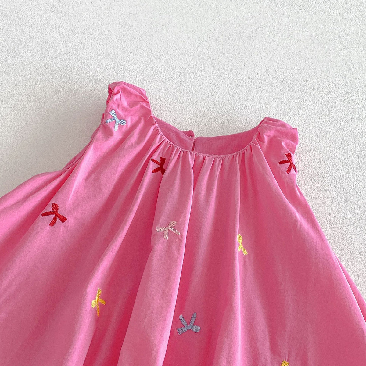 ピンクのキッズワンピース首まわりアップ、ギャザーと刺繍リボン柄