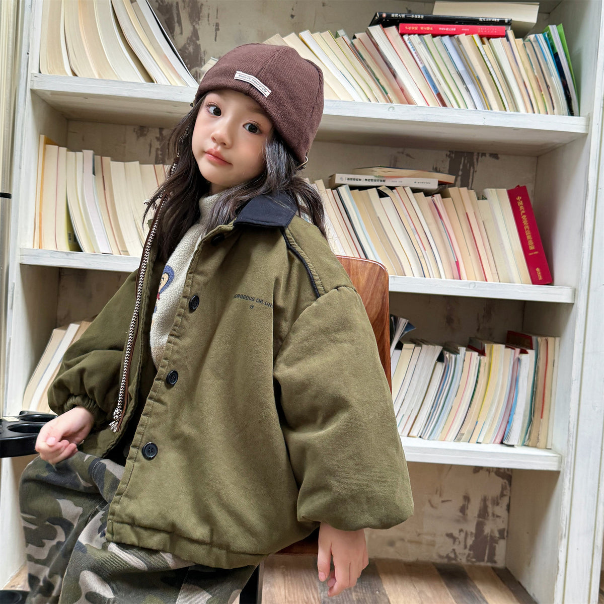 オリーブ色フード付き中綿ジャケット、前ボタンとゆったりした肩回り