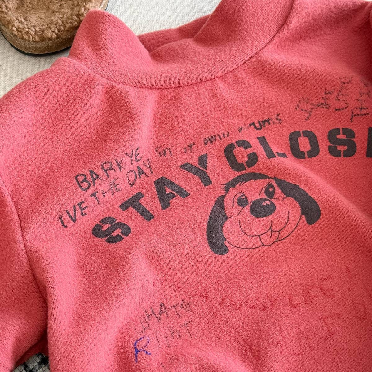赤の長袖裏起毛ハイネックTシャツ、犬イラストとロゴ風文字のアップ