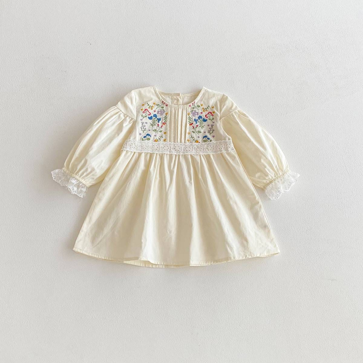 長袖ワンピース(膝丈目安)。クリーム色、前ボタンと花柄刺繍のフレアシルエット
