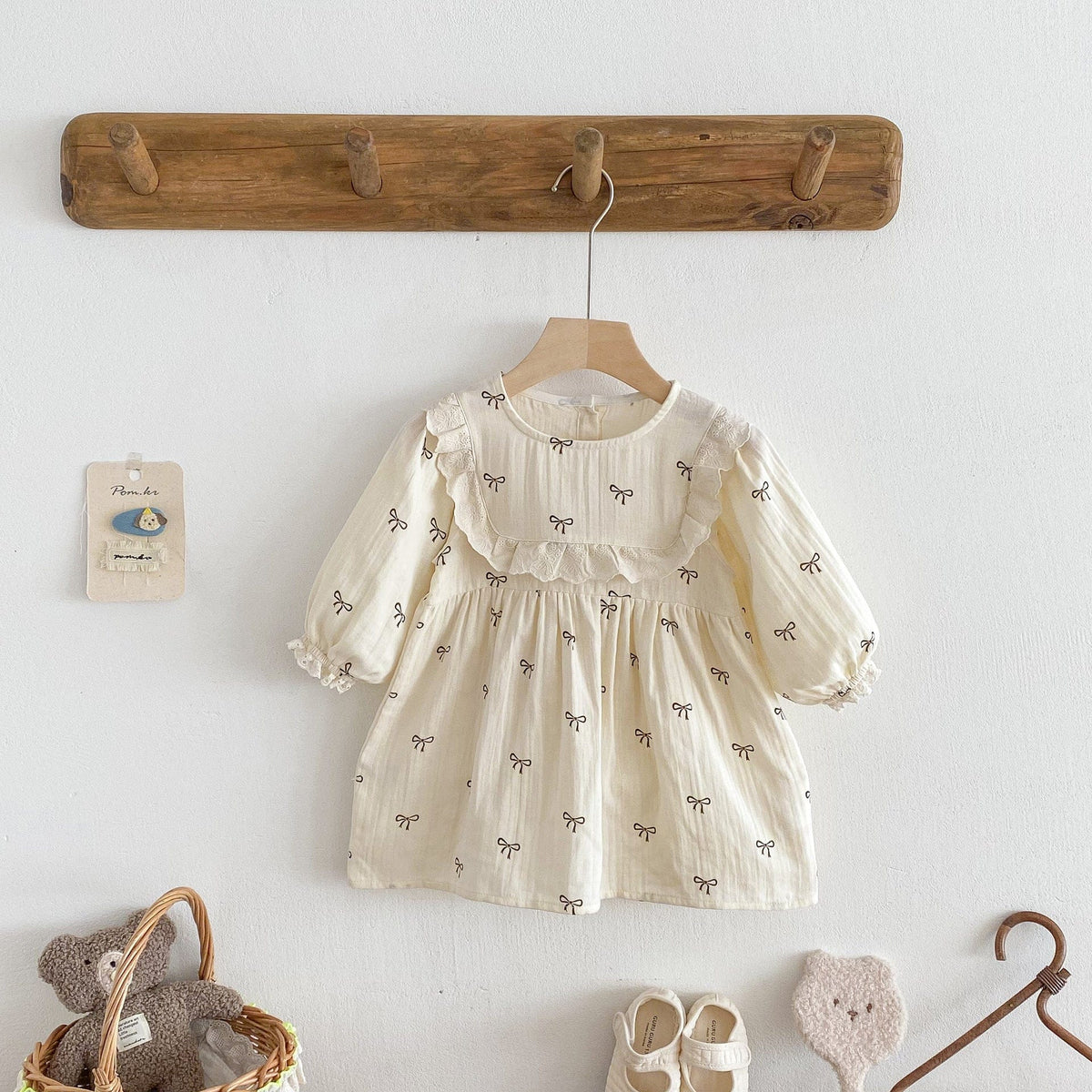 ベージュのリボン柄長袖ワンピース、フリル襟とフレアシルエットの子ども服