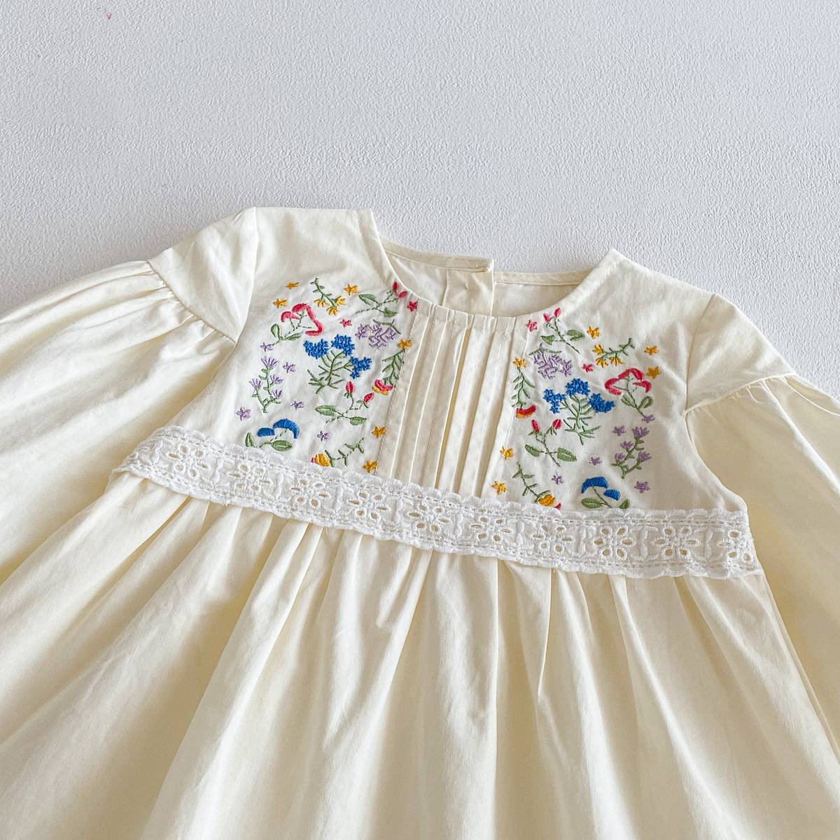長袖ワンピース胸元アップ。クリーム色、花柄刺繍とレースの切替