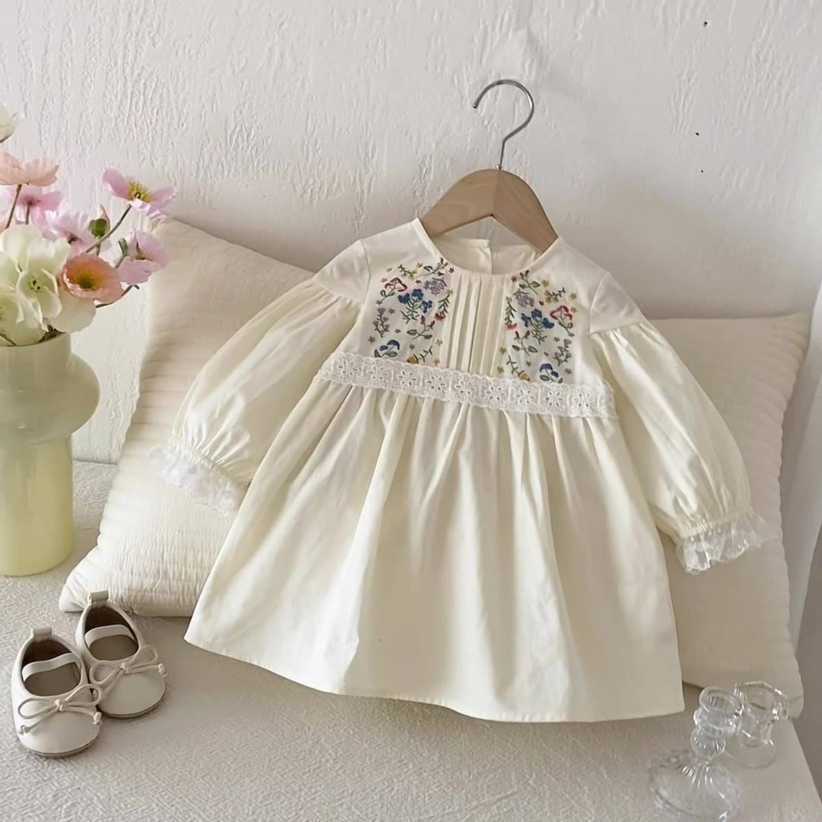 長袖ワンピース(膝丈目安)。クリーム色、胸元の花柄刺繍とレース切替