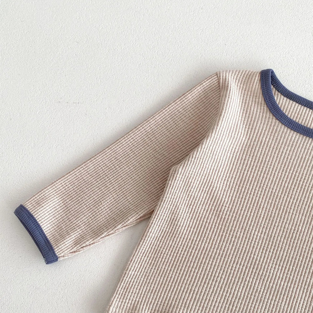 ベージュの子ども長袖Tシャツの袖、青系ライン入りリブ仕立て