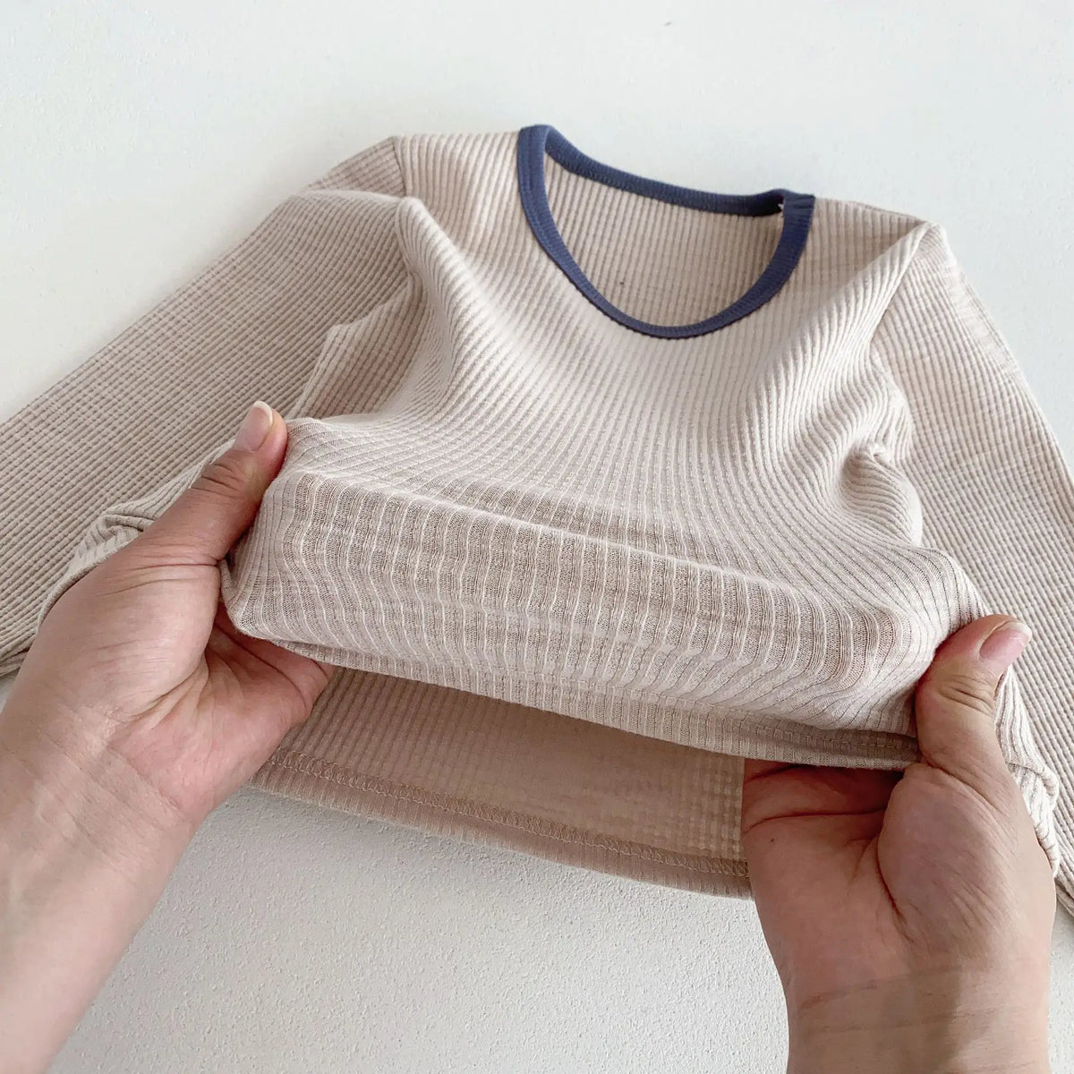 ベージュの子ども長袖Tシャツ、リブ仕立ての襟と袖口(青系ライン)