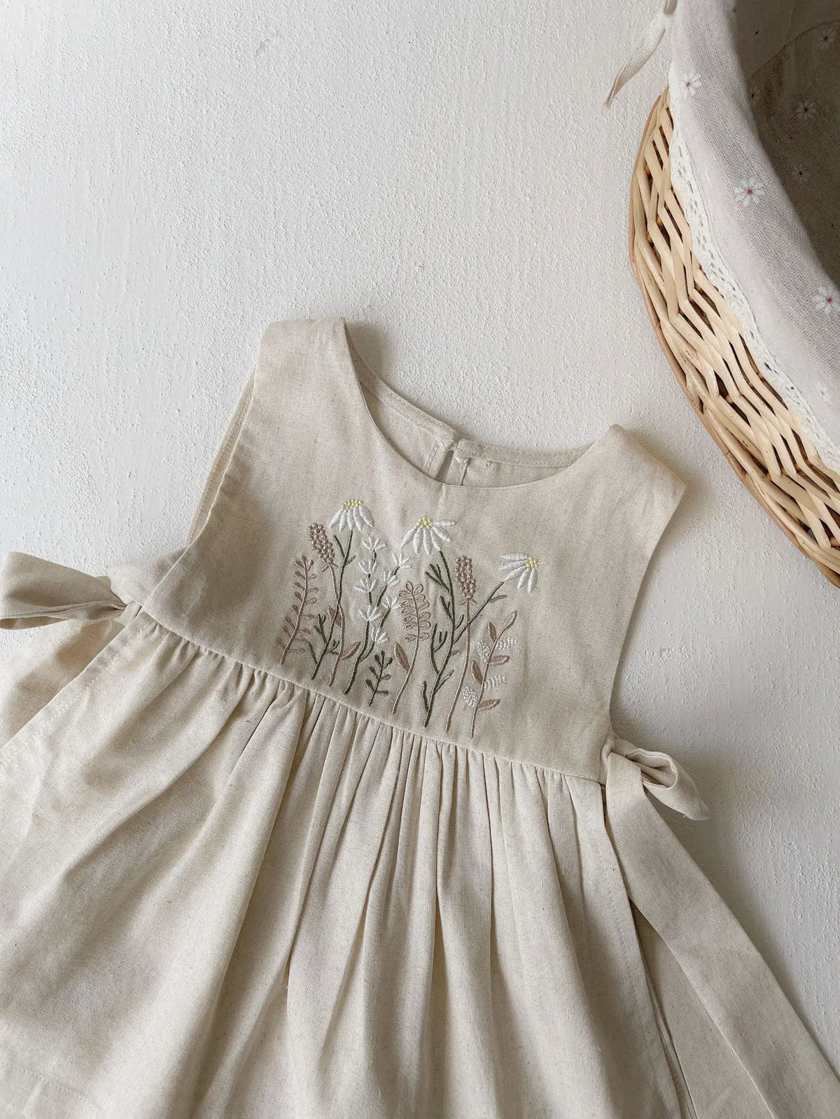 生成り色ノースリーブワンピース、胸元の花柄刺繍とギャザーの広がるスカート