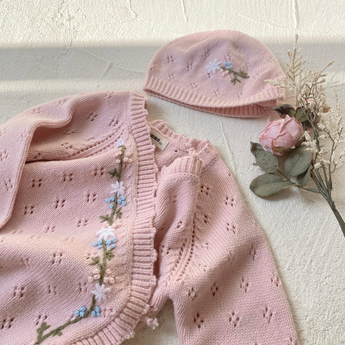 ベビー用ライトピンクのニット帽と長袖ロンパース(花刺繍の縁取り)
