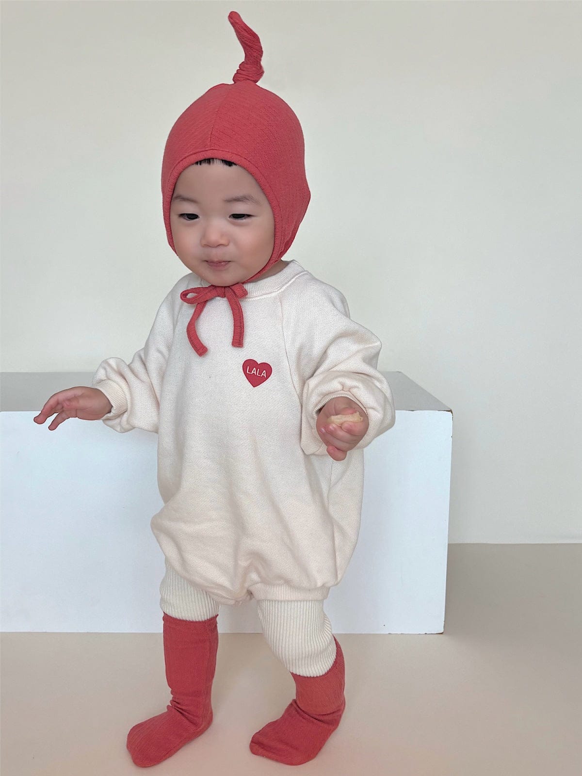 ハート刺繍入りクリーム色スウェットロンパース、ラグラン袖・フード付き、紐とリブソックス風配色