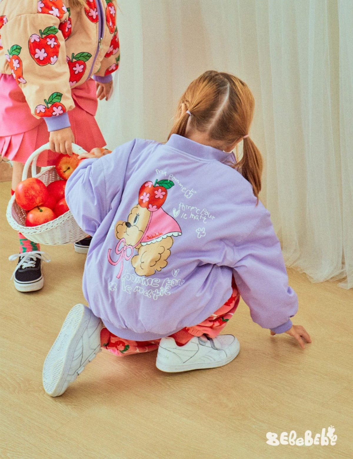 背面りんご柄のライトパープルブルゾンとピンクフリルスカート