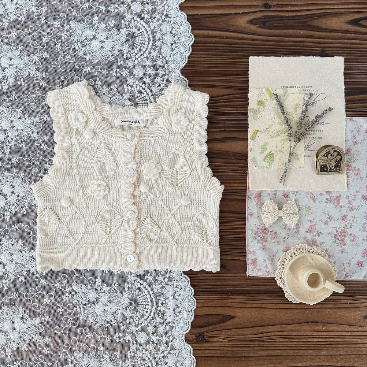 ベビーキッズ用ニットベスト(生成り)。花柄クロシェ刺繍の前あき・前ボタン留め