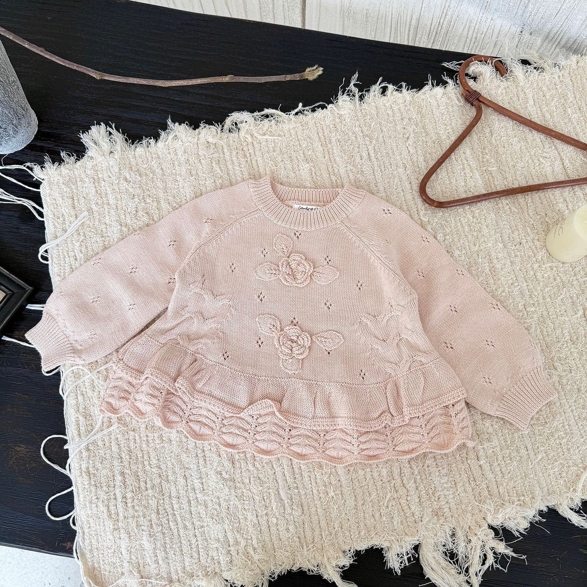 ライトピンクのニットプルオーバー、フラワー刺繍とフリル裾、長袖