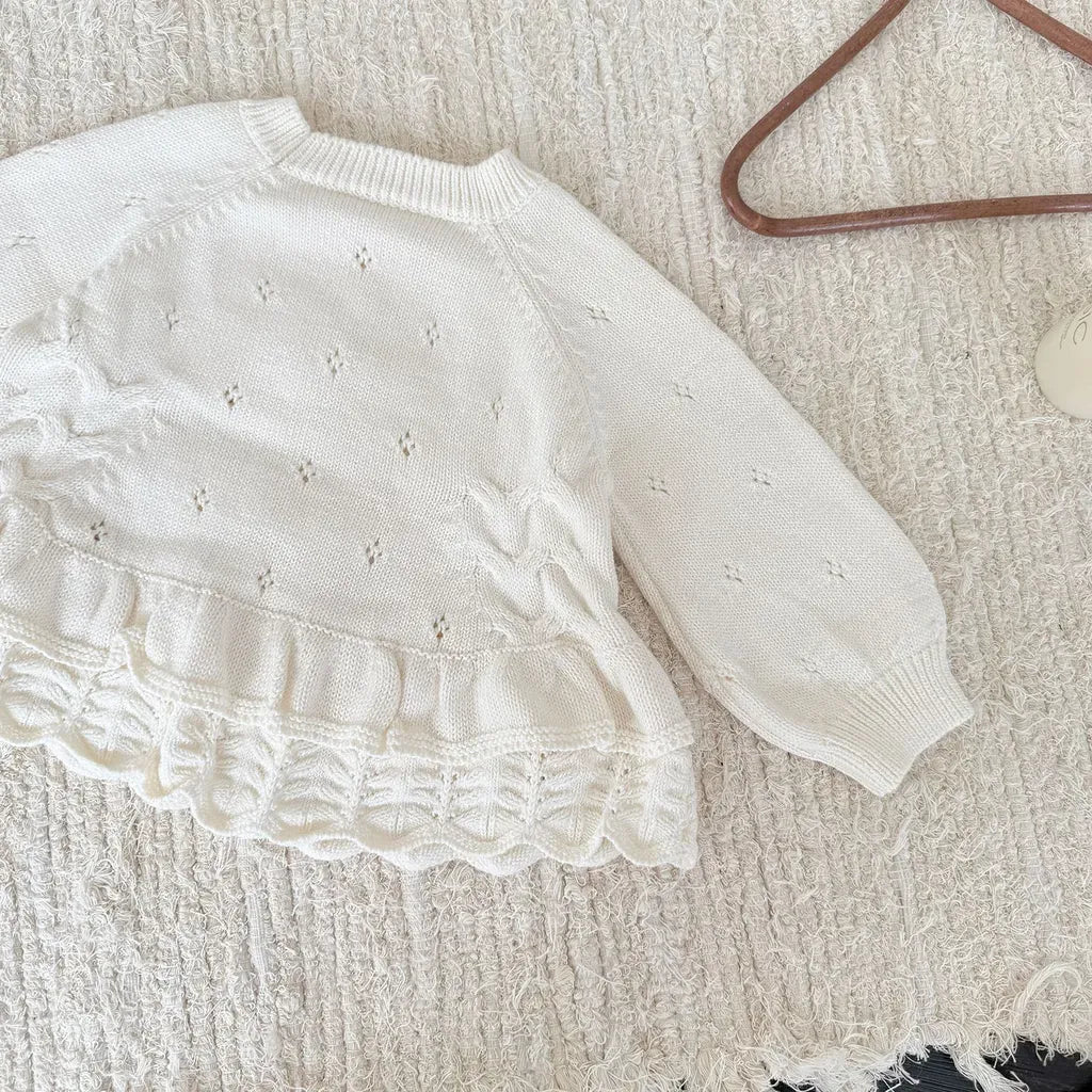 クリームホワイトのニットプルオーバー、フラワー刺繍とフリル裾の長袖