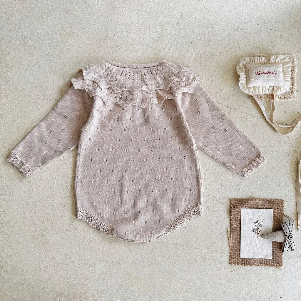 薄いピンクのニットロンパース、背面フリル襟のデザインが見える