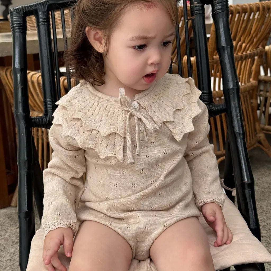 生成りのフリル襟リボン付き長袖ニットロンパースの子ども
