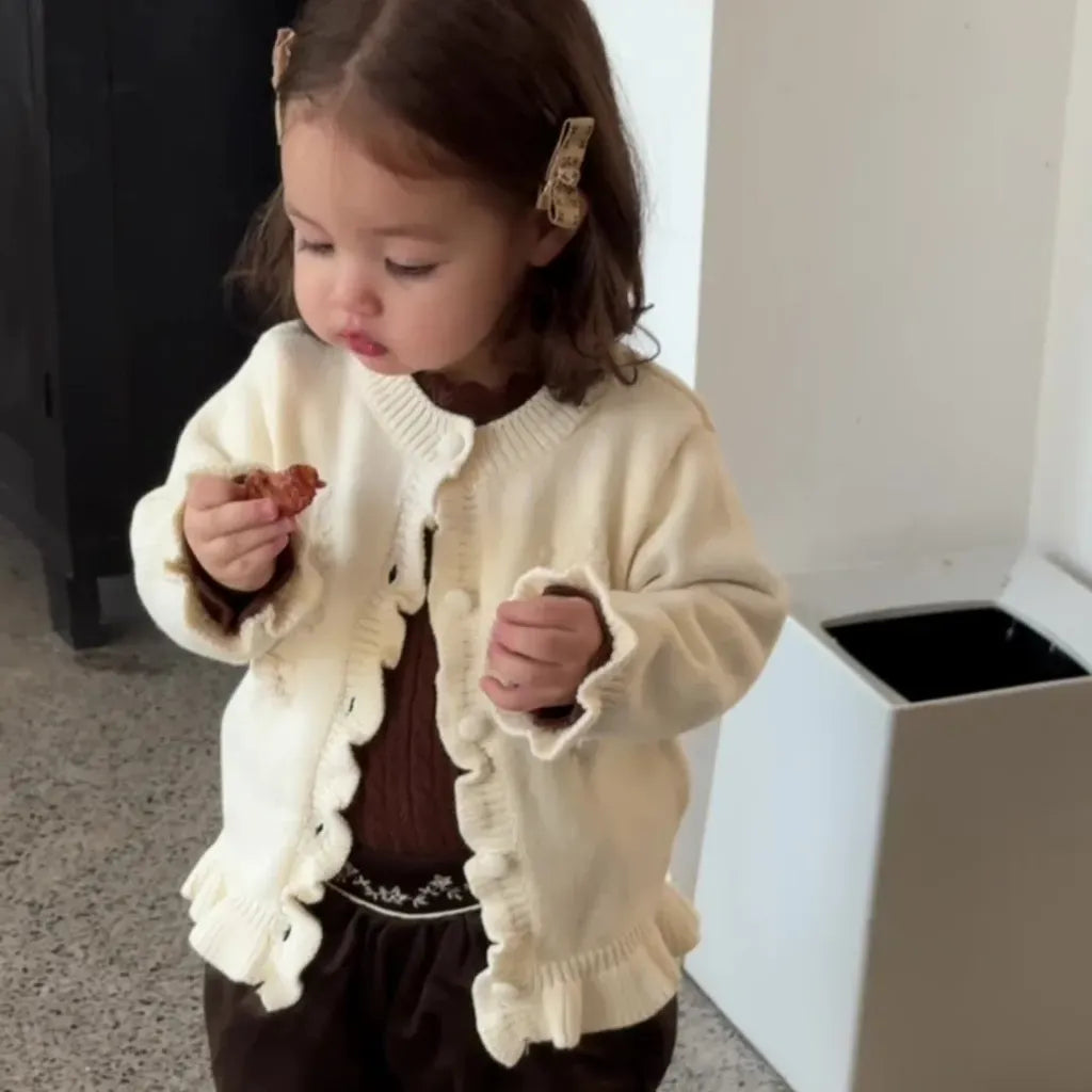 アイボリーのレース風メロウ付きハイネックケーブルニットトップスを着た子ども