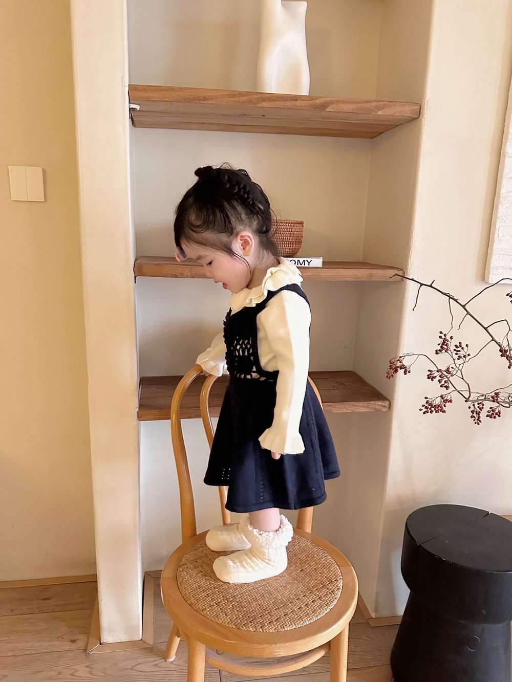 生成りの長袖ニット、後ろはフリルネックが見える。