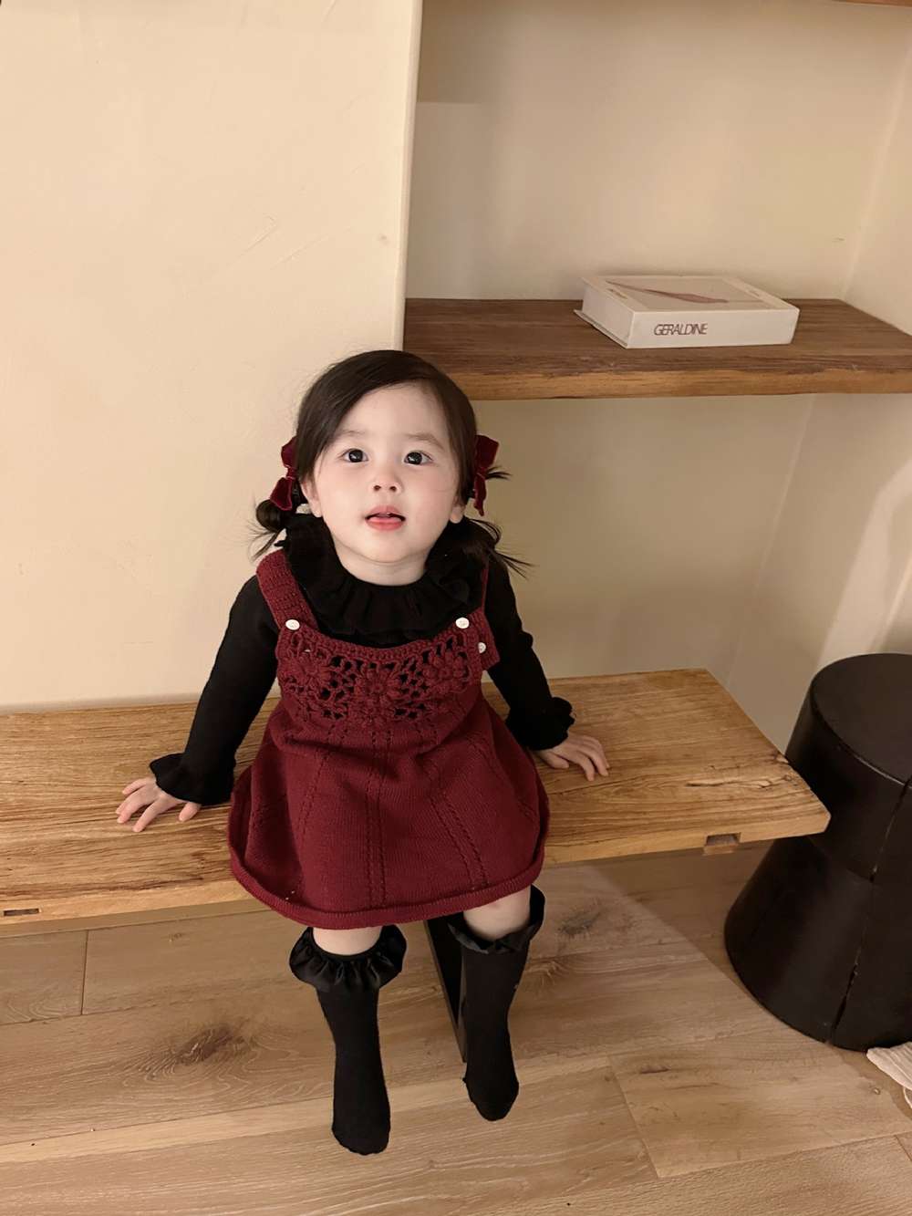 黒の長袖ニット、フリルネック付き。