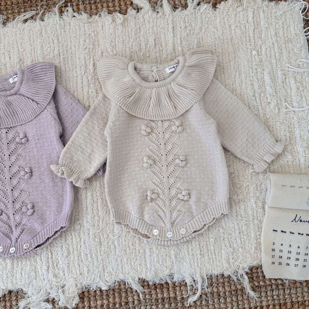 長袖ニットロンパース(オフホワイト)ラッフル襟とフリル、中央の花柄風刺繍