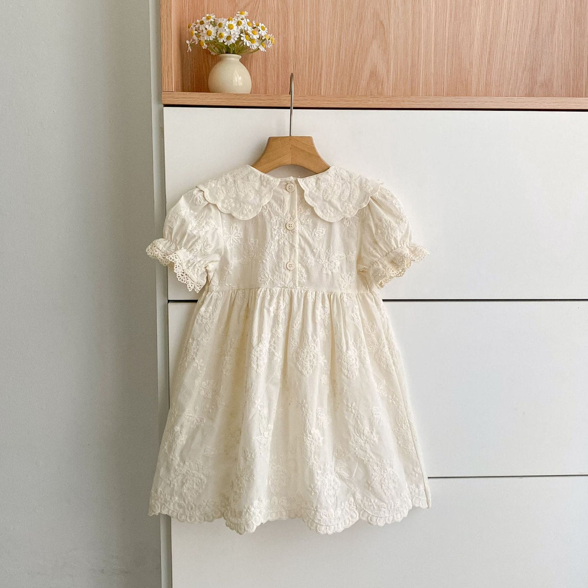 アイボリーの刺繍入りパフスリーブロンパース、フリル襟と前ボタン付き