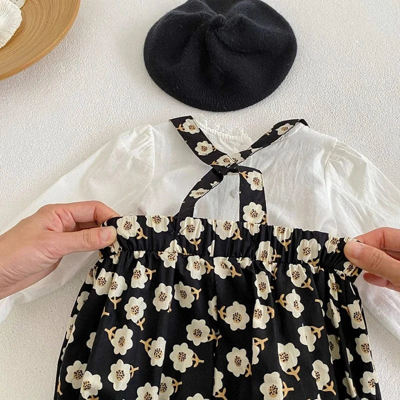 黒い花柄サロペットの胸元アップ。フリル仕立てでボタン留め