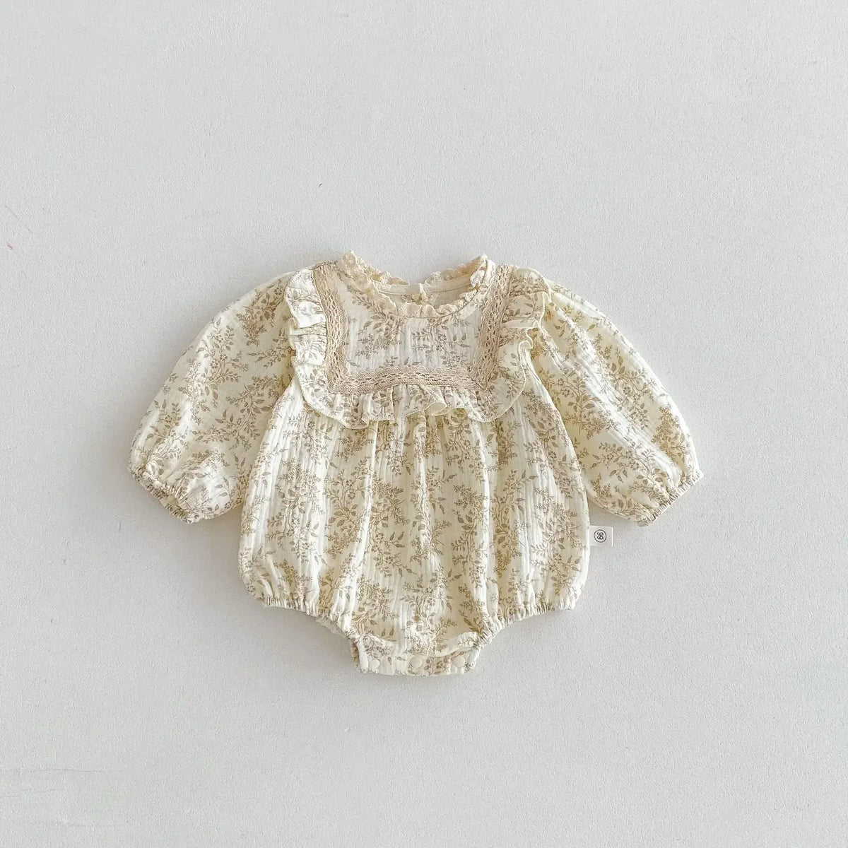 ベビー用ボディスーツ 長袖フリル付き、花柄プリントの淡いアプリコット色