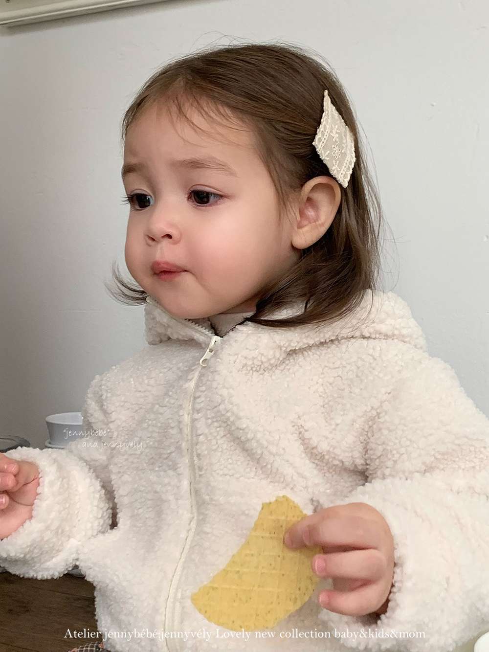 生成りのフード付きロンパース、前ジップとチェック柄フリルスカートが見える