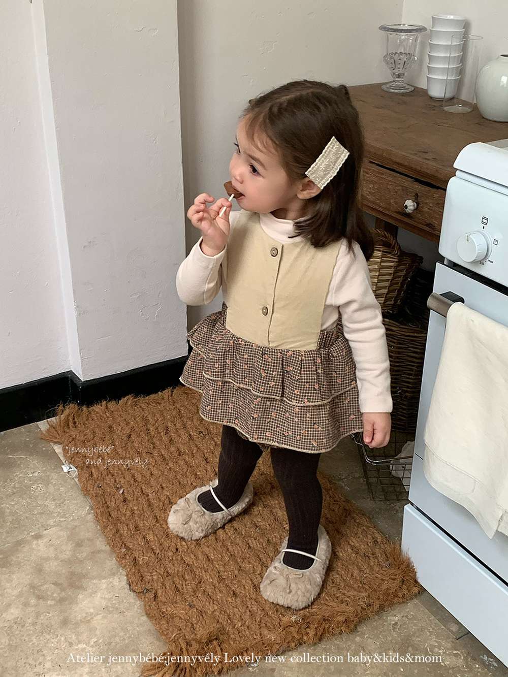 ベージュのベビー服トップとチェックフリルスカート、濃色ソックス