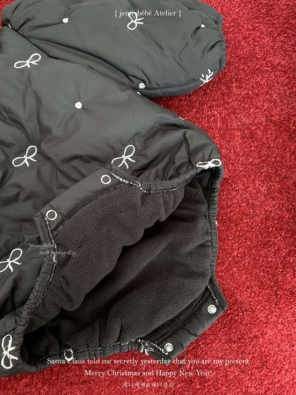 黒の中綿ロンパースのアップ、リボン刺繍とかぶさるフード風インナー