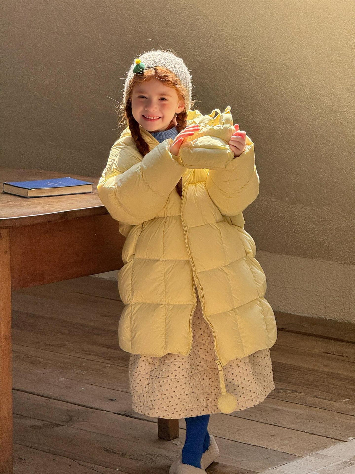 イエローダウンコートの子ども、腕を広げて笑顔