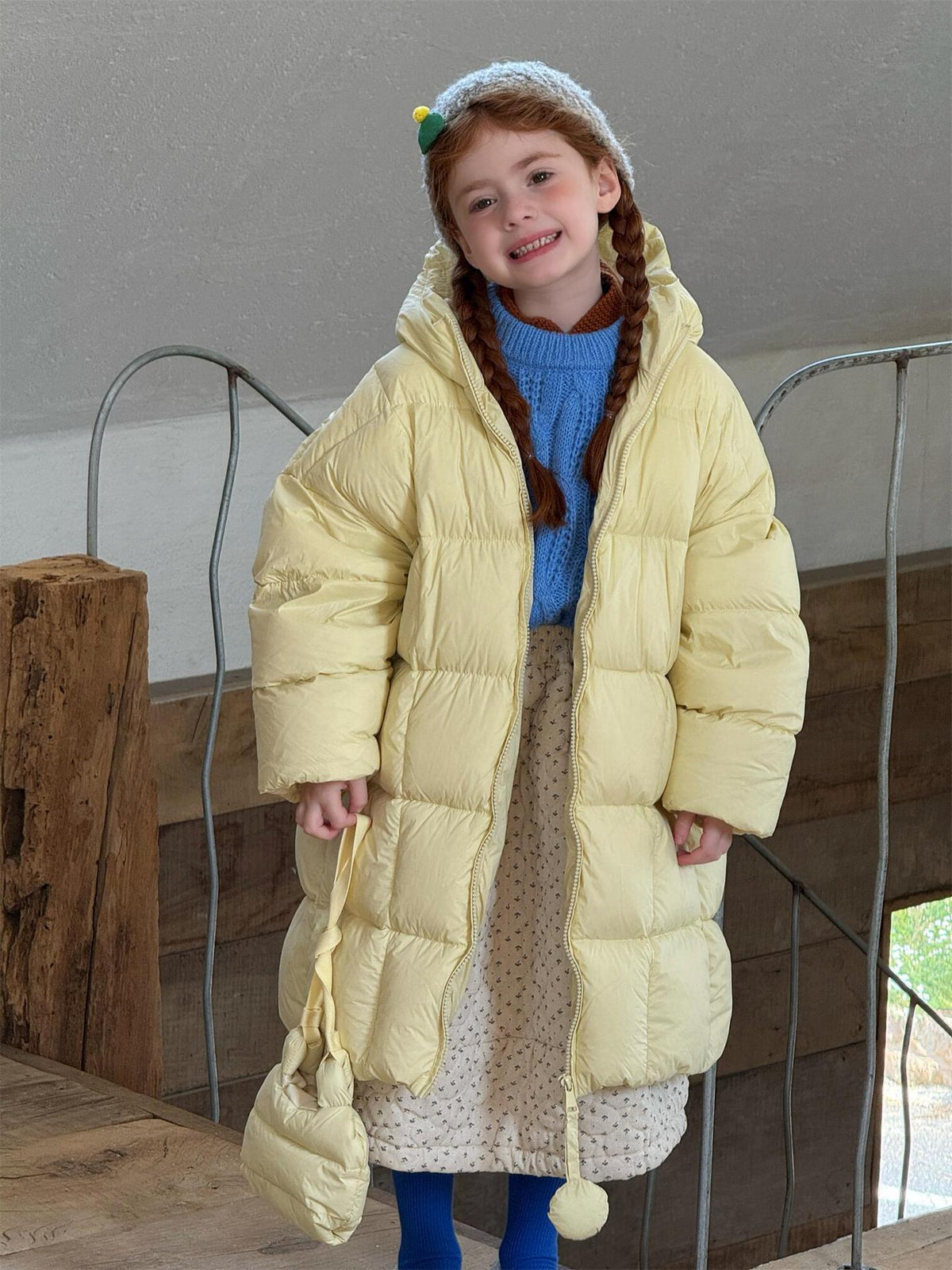 フードボア付きイエローダウンコートを着た子ども、立ち姿