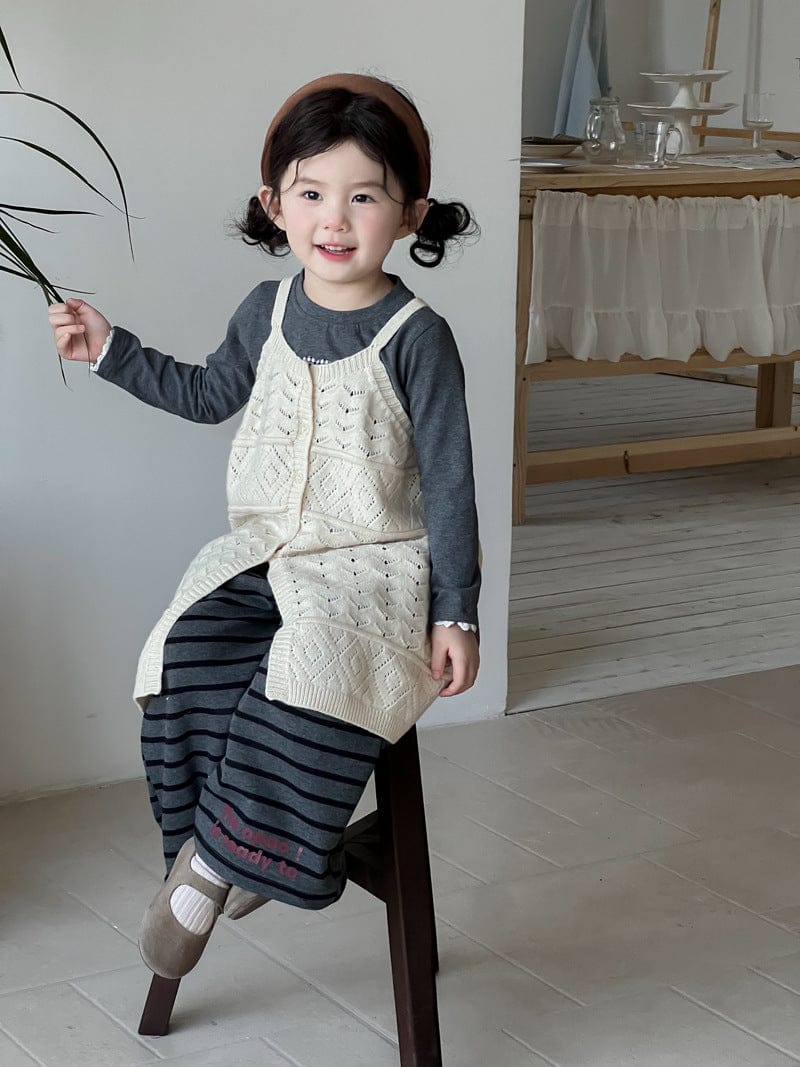 生成りニットビブベストとボーダー柄ロングパンツ(椅子に乗る)