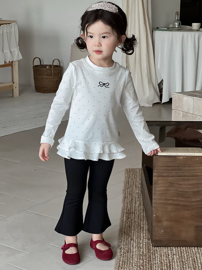 白ドット柄長袖Tシャツ裾フリル(リボン)と黒フレアロングパンツ、斜め前姿