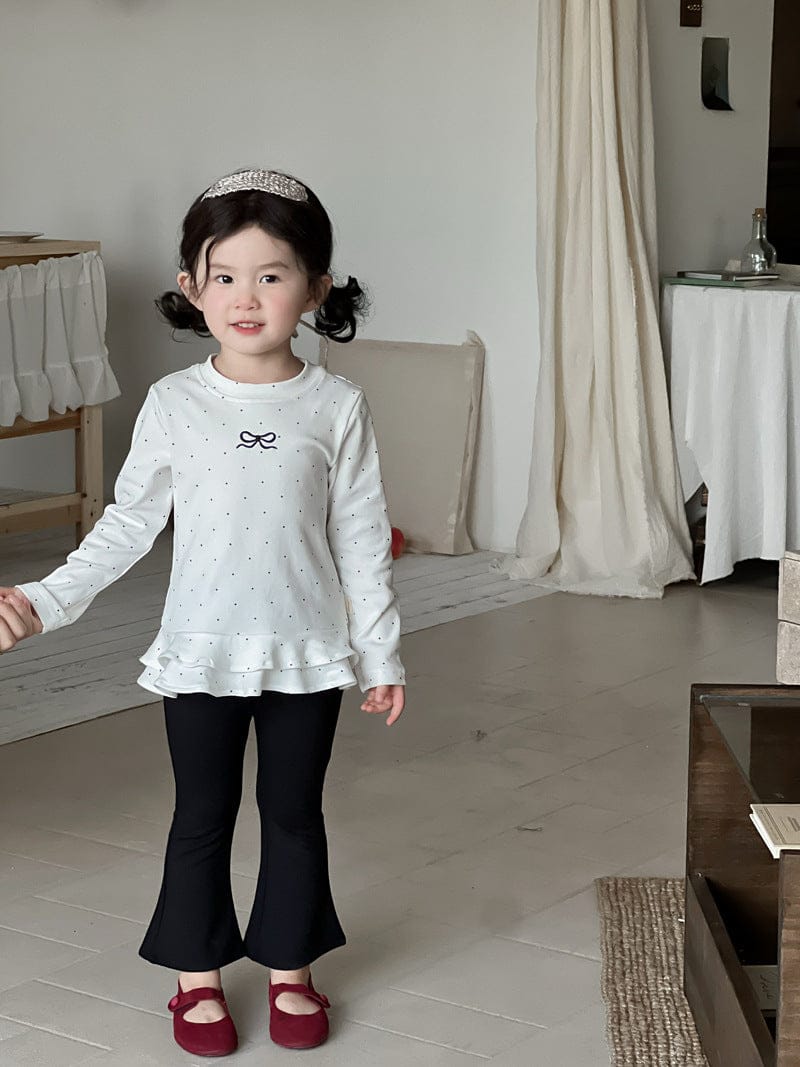 白のリボン刺しゅうドット柄長袖Tシャツ(裾フリル)と黒フレアパンツ