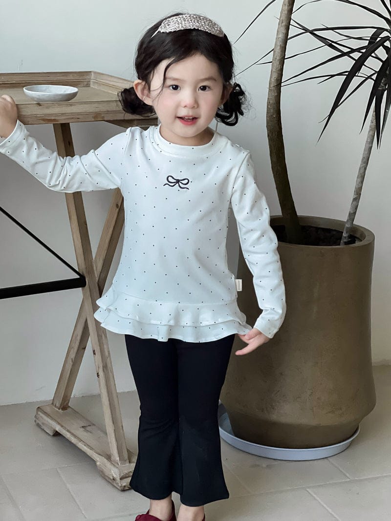 白ドット柄長袖Tシャツ裾フリル(リボン)と黒フレアパンツ、横向き全身