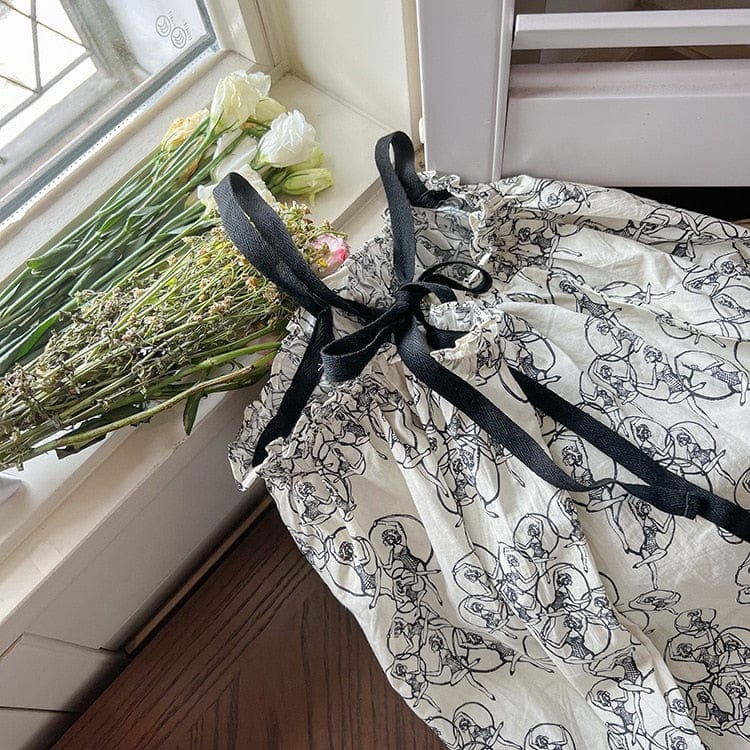 白地ワンピースの背面、黒ストラップと総柄プリント