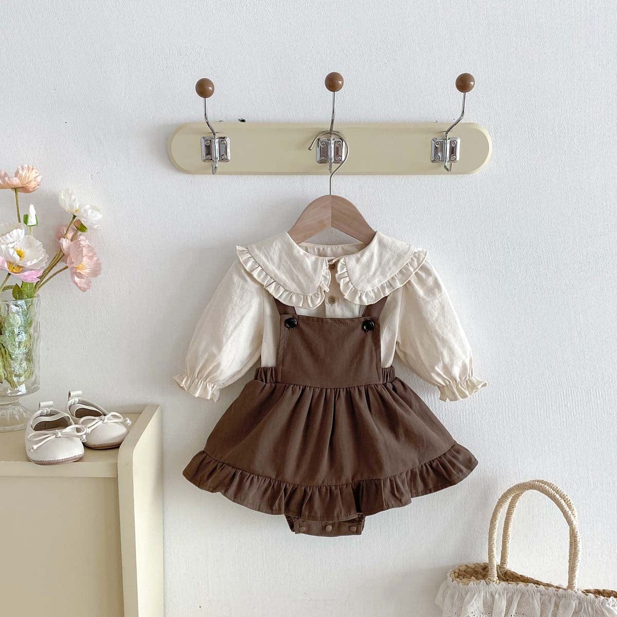 ハンガー掛けのベビー服、白いフリル襟シャツとブラウンのサロペット