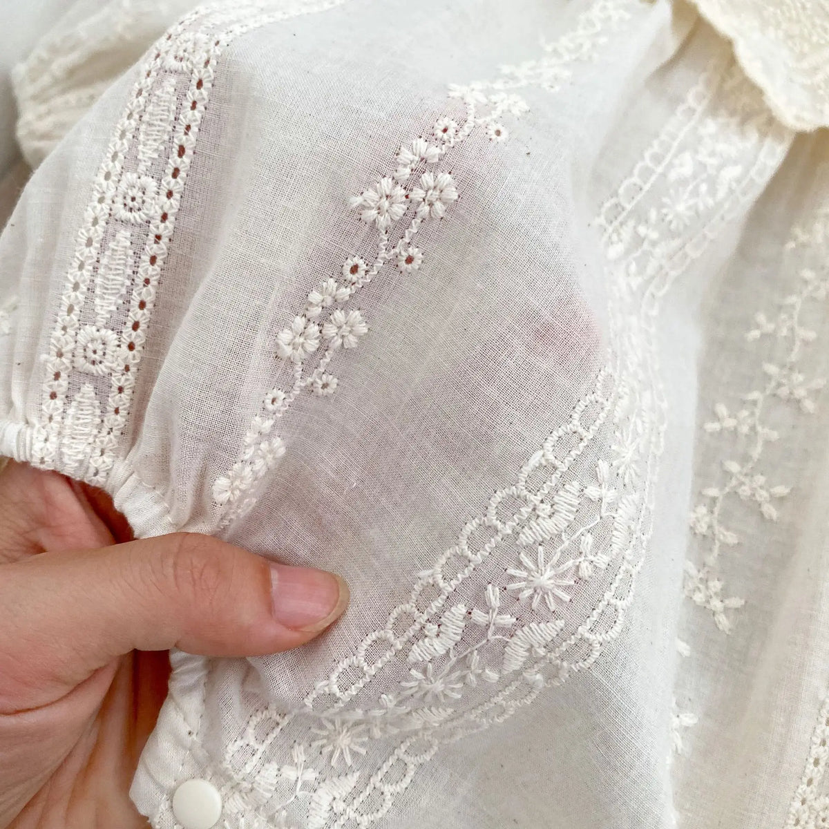 長袖ドレスの胸元アップ、繊細なレース刺繍と花柄モチーフ、ベージュ系