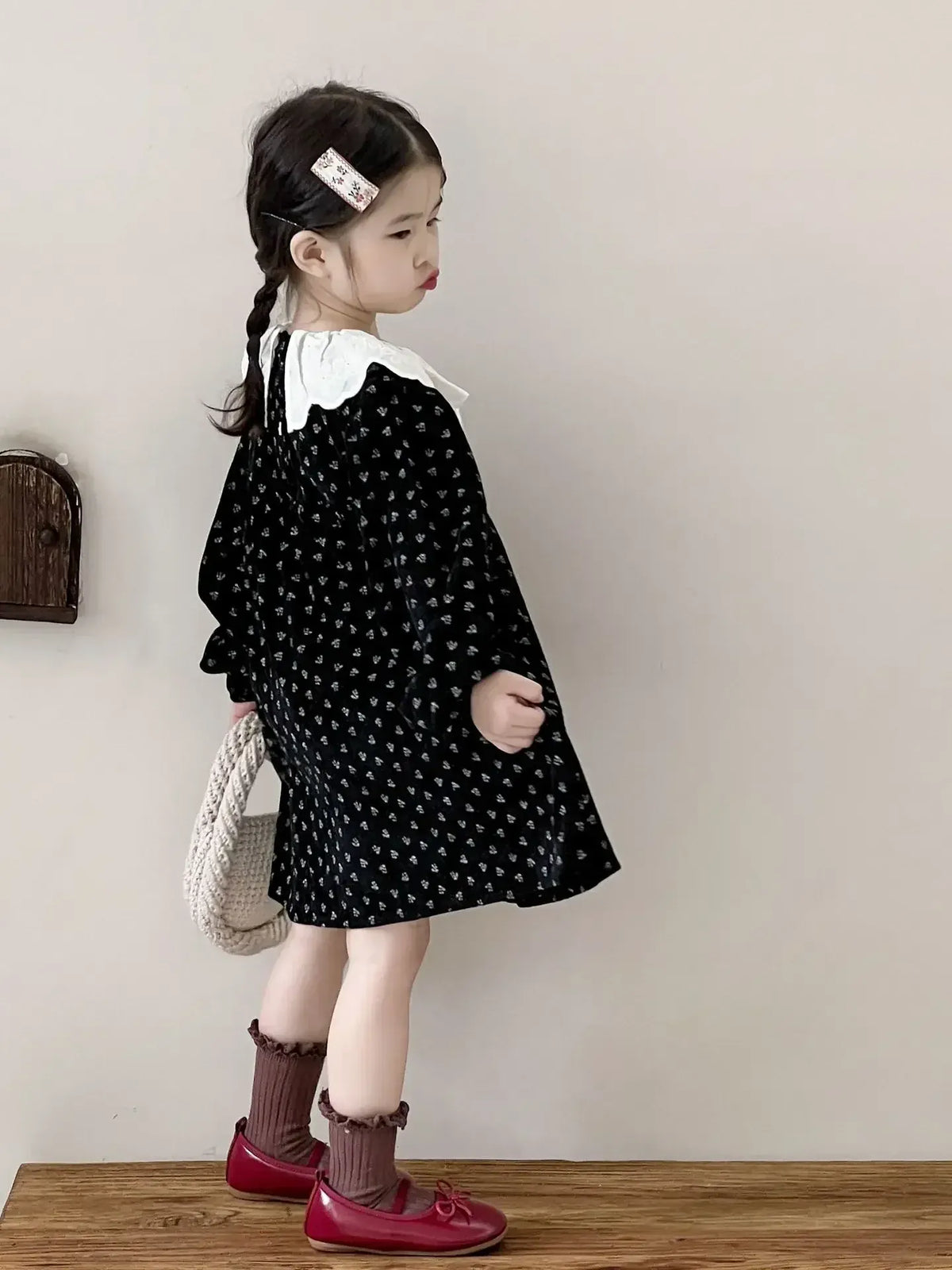 黒地小花プリントのキッズワンピース、白いラッフル襟と長袖