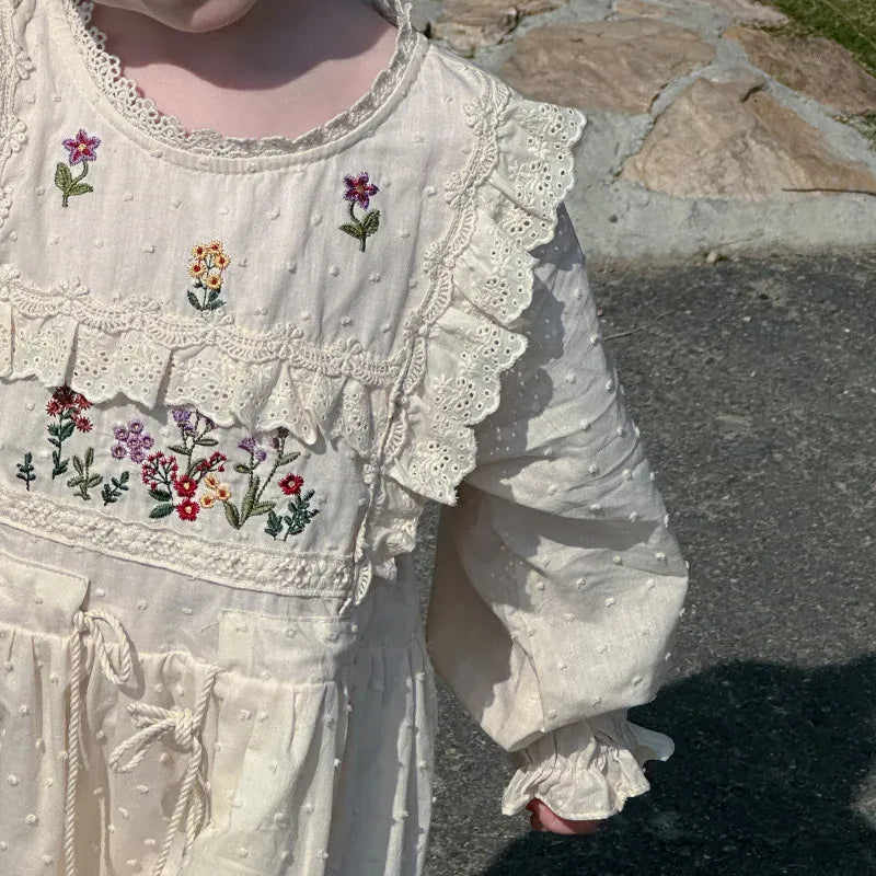 生成りのワンピース胸元アップ、花刺繍とレースのフリル装飾