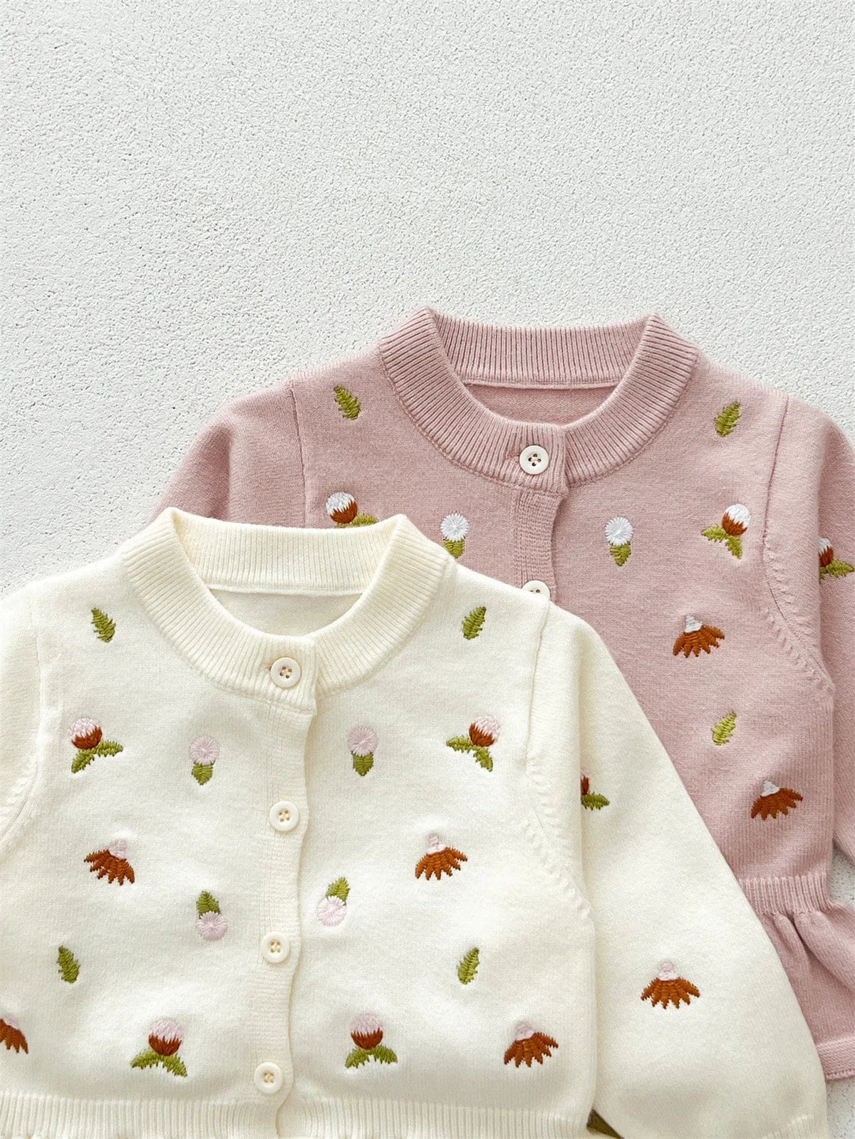 ベビーカーディガン(白と薄ピンク)長袖ニット、前開きボタン、刺繍柄入り