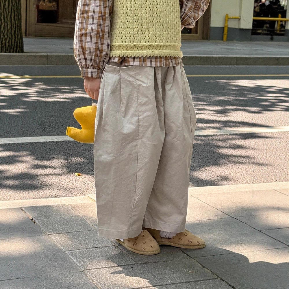 ベージュのテーパードパンツ、全体的にゆったりしたコクーンシルエット