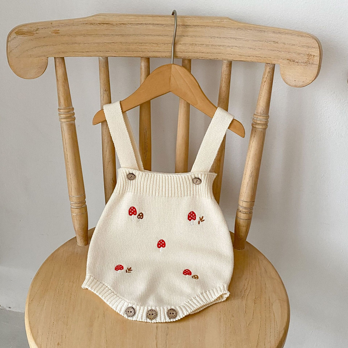 きのこ刺繍ロンパース クリーム系、肩紐付き、木目ボタン、赤いきのこ柄