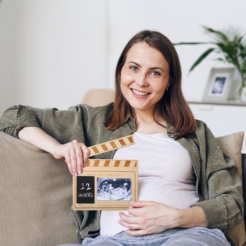 マタニティ中の女性が持つ月齢フォトカード、12 weeksの印字と胎内写真枠