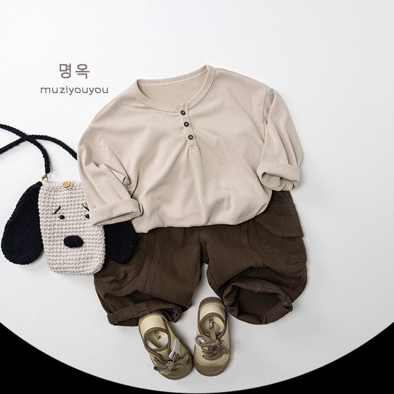 ベージュ系の長袖ヘンリーネックTシャツ、前立てのボタン