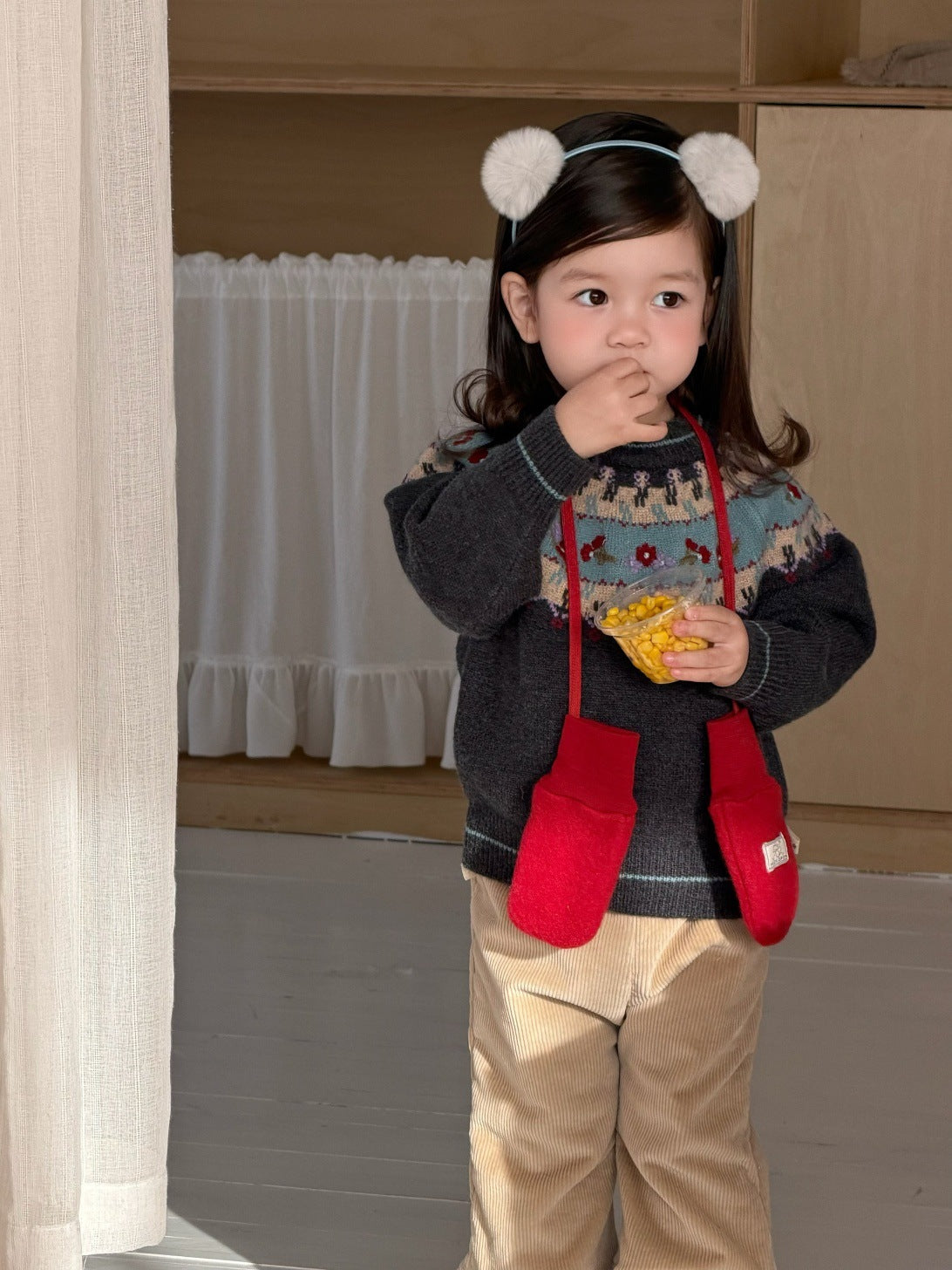 側面の濃色フェアアイル柄ニットセーターとベージュ裏フリースパンツ