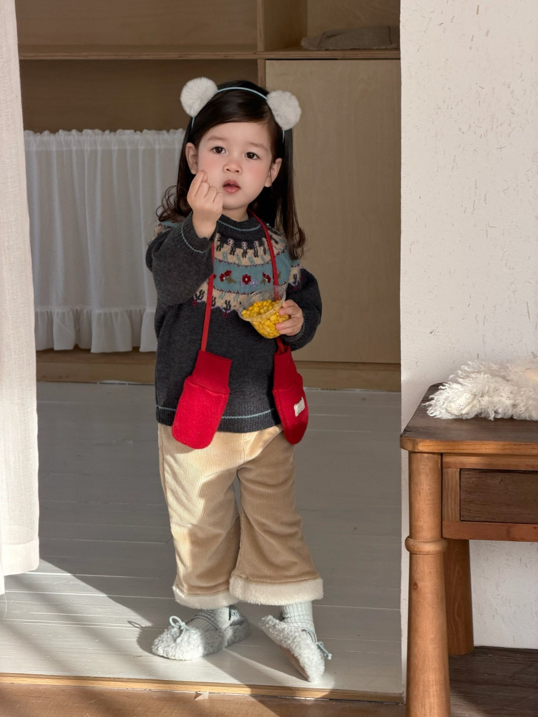フェアアイル柄ニットセーターと裏フリースのベージュパンツ、赤い前ポケット風