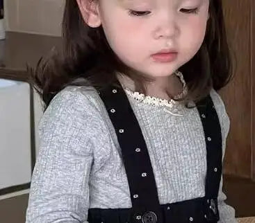子どもの着用アップ、グレー長袖トップと黒ドットのサスペンダースカート