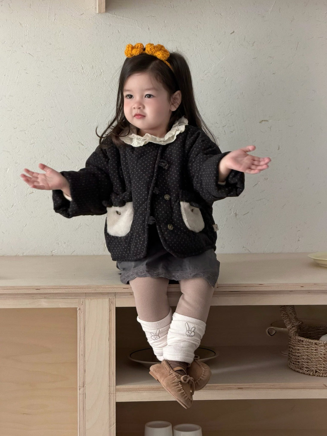 水玉プリントの黒いキッズブルゾン、両手を広げた着用姿(白いポケット)