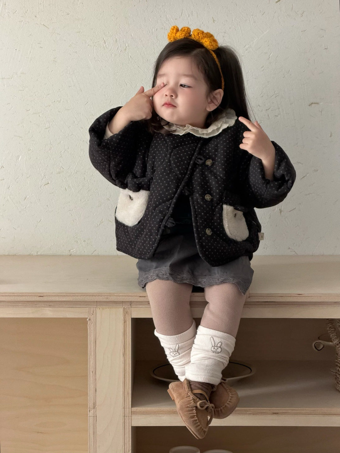 子ども用ドット柄ブルゾン、フリル襟と白いファー風ポケットの黒い上着